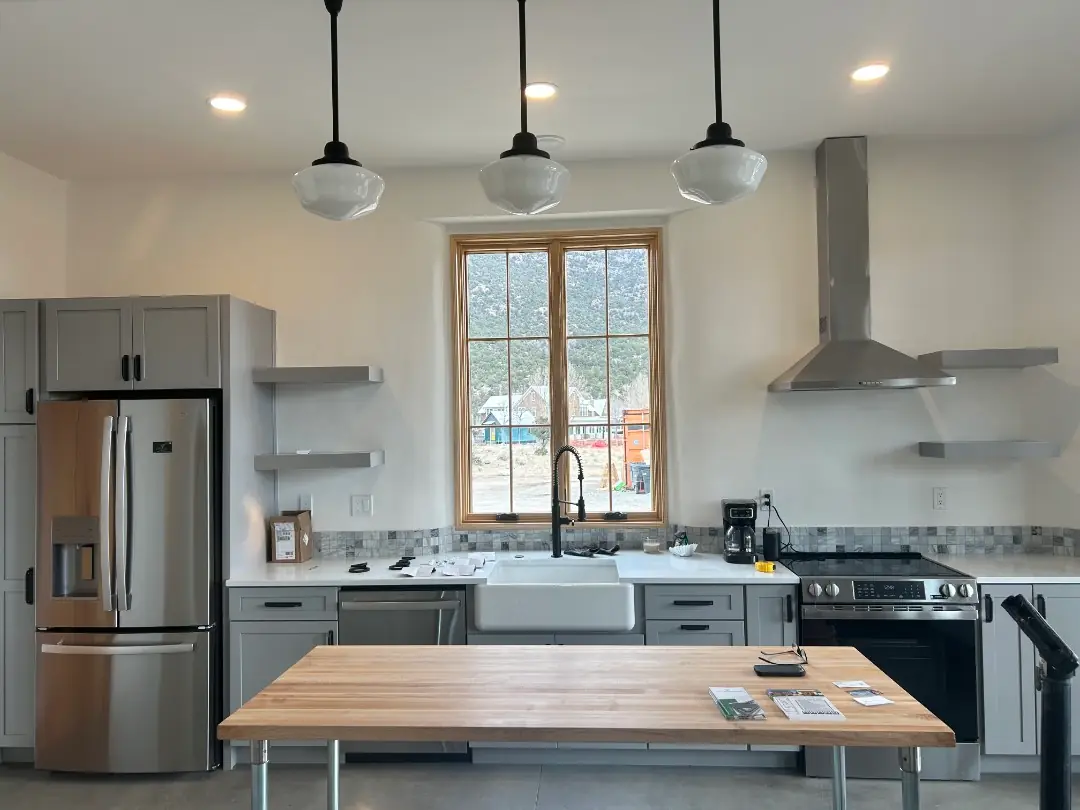 New kitchen with three schoolhouse pendant lights over the island and recessed ceiling lights