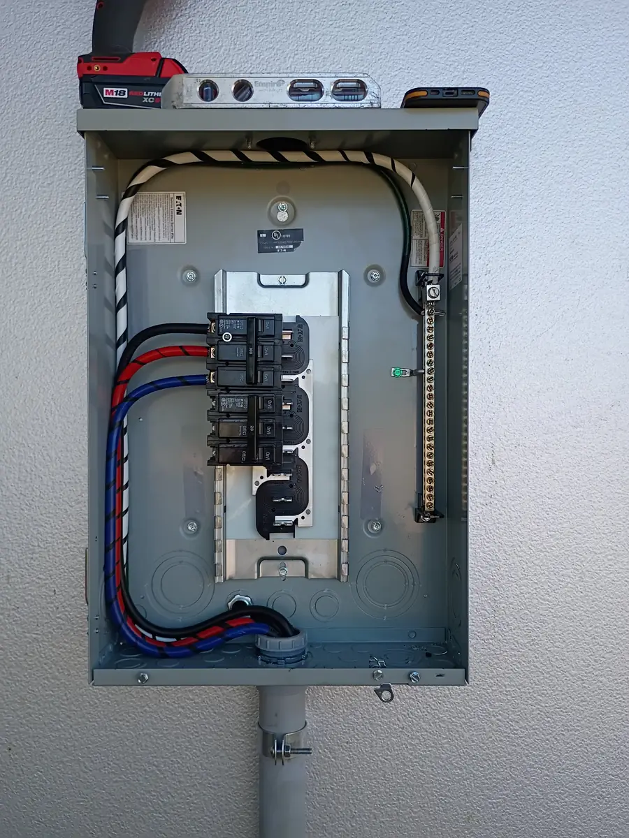 Outdoor Eaton three-phase panel with color-coded feeder conductors in PVC conduit